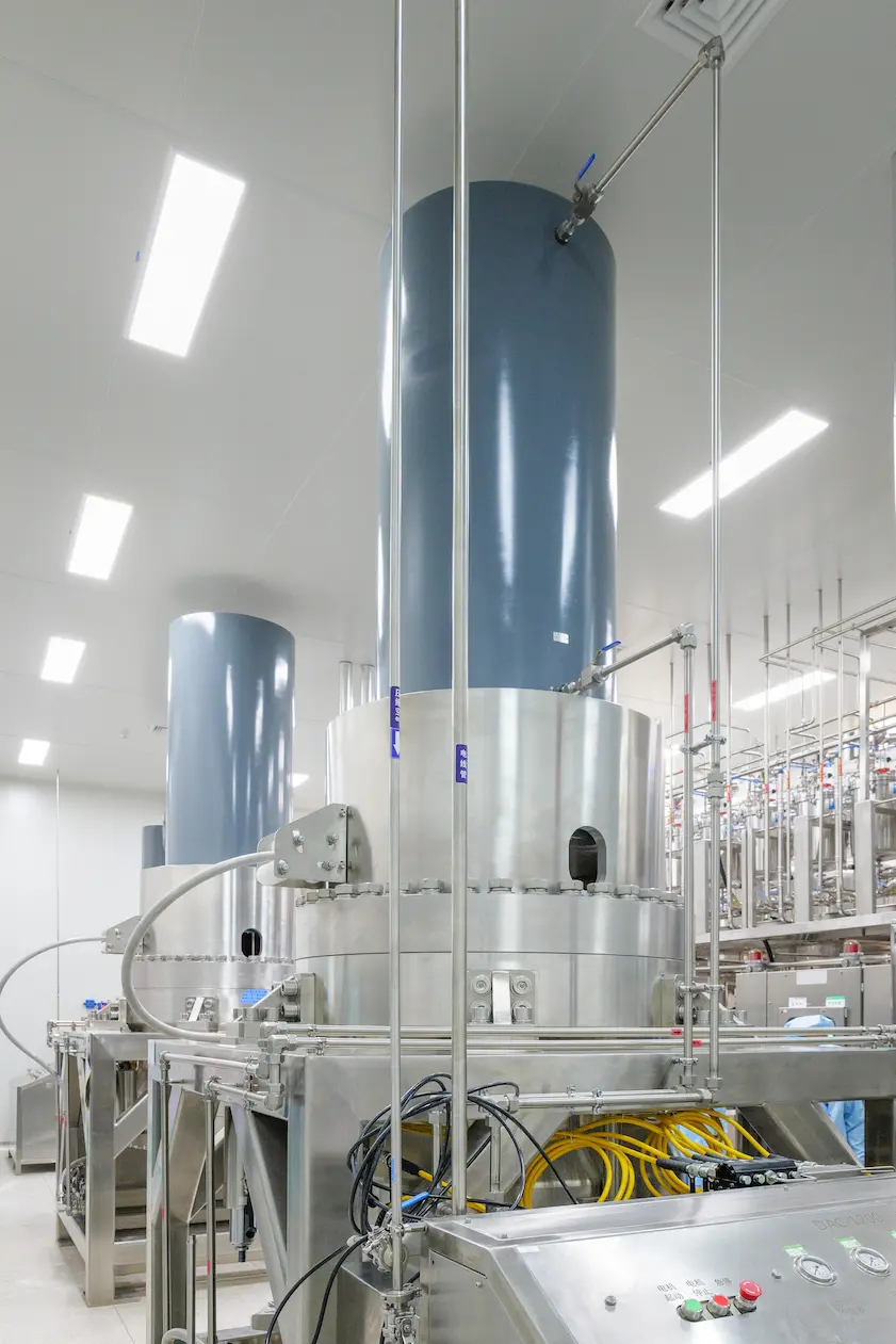 Stainless steel reactor system with overhead piping and control panel inside a cleanroom at JYMed’s Hubei JXBio peptide manufacturing site.