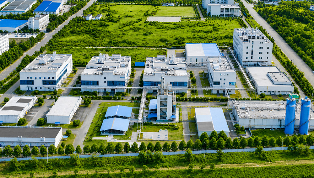 Aerial photo of JYMed’s Hubei JXBio manufacturing facility, featuring GMP buildings, green spaces, and industrial infrastructure across a 300-acre campus.