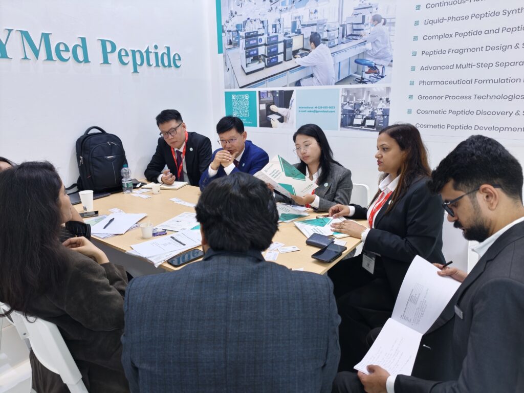 JYMed Peptide representatives and pharmaceutical industry visitors participating in a business meeting around a conference table at CPHI Milan 2026.